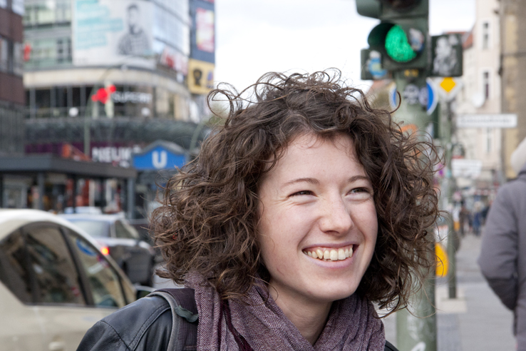 Deutsch lernen Berlin; Schülerin steht lächelnd auf der Karl-Marx-Straße